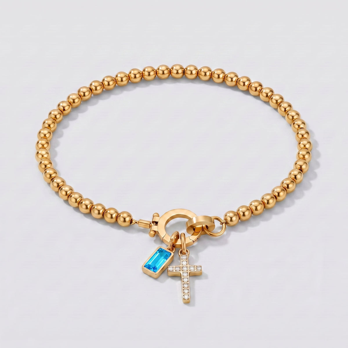 Pulsera dorada de cuentas con cruz y piedra de nacimiento topacio azul de diciembre.