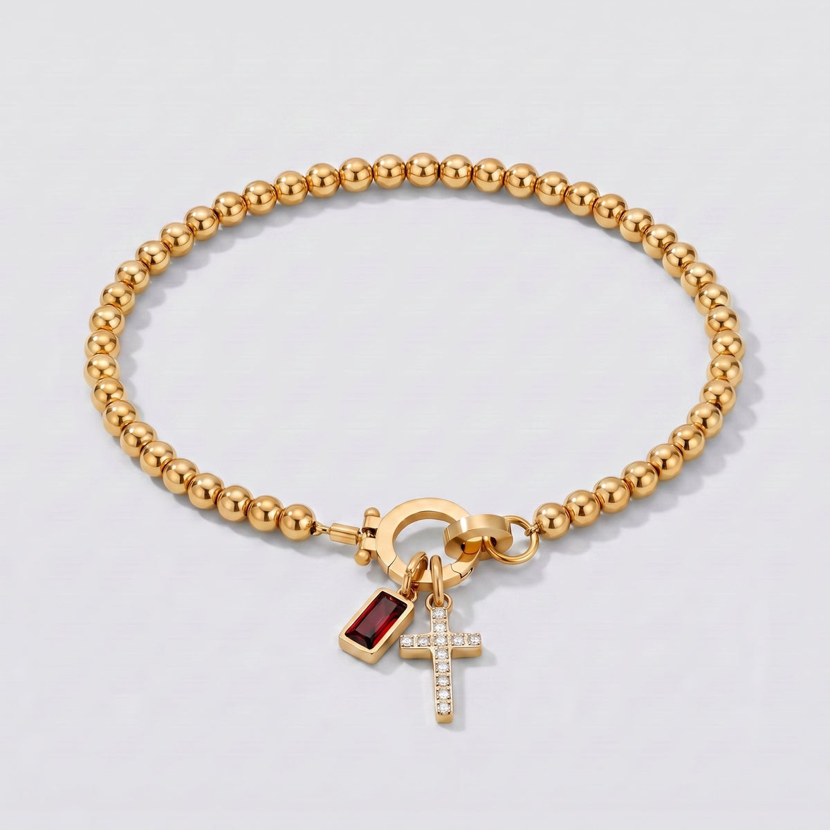 Pulsera dorada de cuentas con cruz y piedra de nacimiento granate de enero.