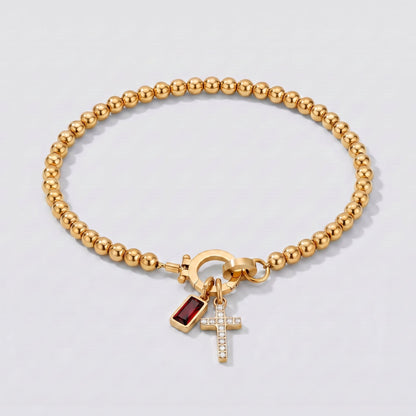 Pulsera dorada de cuentas con cruz y piedra de nacimiento granate de enero.