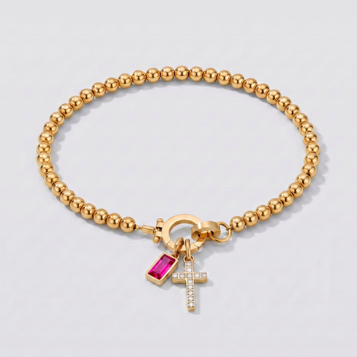 Pulsera dorada de cuentas con cruz y piedra de nacimiento rubí de julio.
