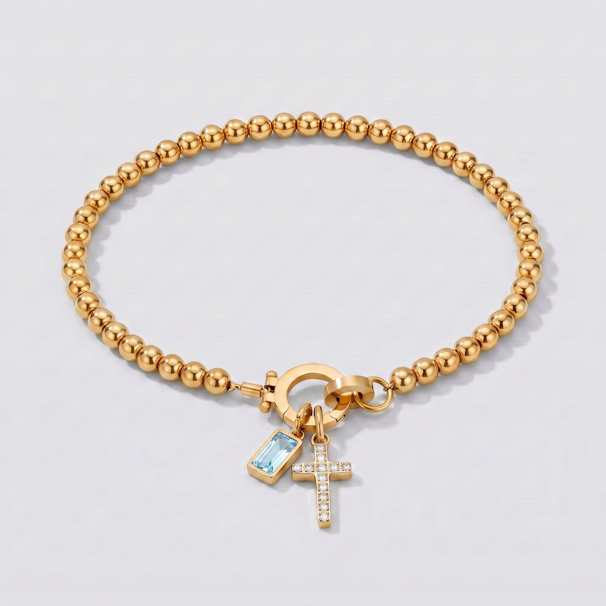 Pulsera dorada de cuentas con cruz y piedra de nacimiento aguamarina de marzo.