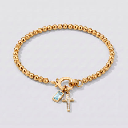 Pulsera dorada de cuentas con cruz y piedra de nacimiento aguamarina de marzo.