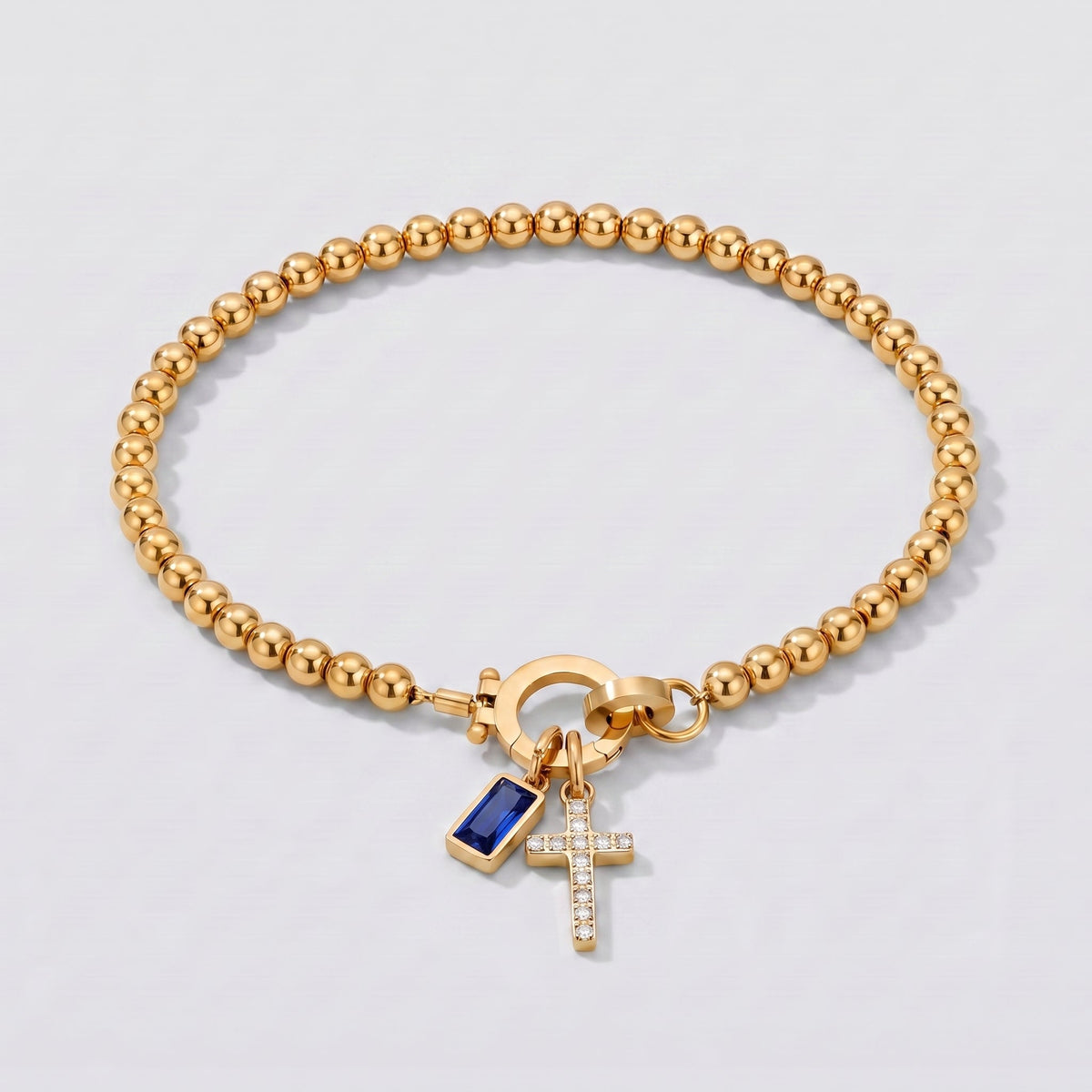 Pulsera dorada de cuentas con cruz y piedra de nacimiento zafiro azul de septiembre.