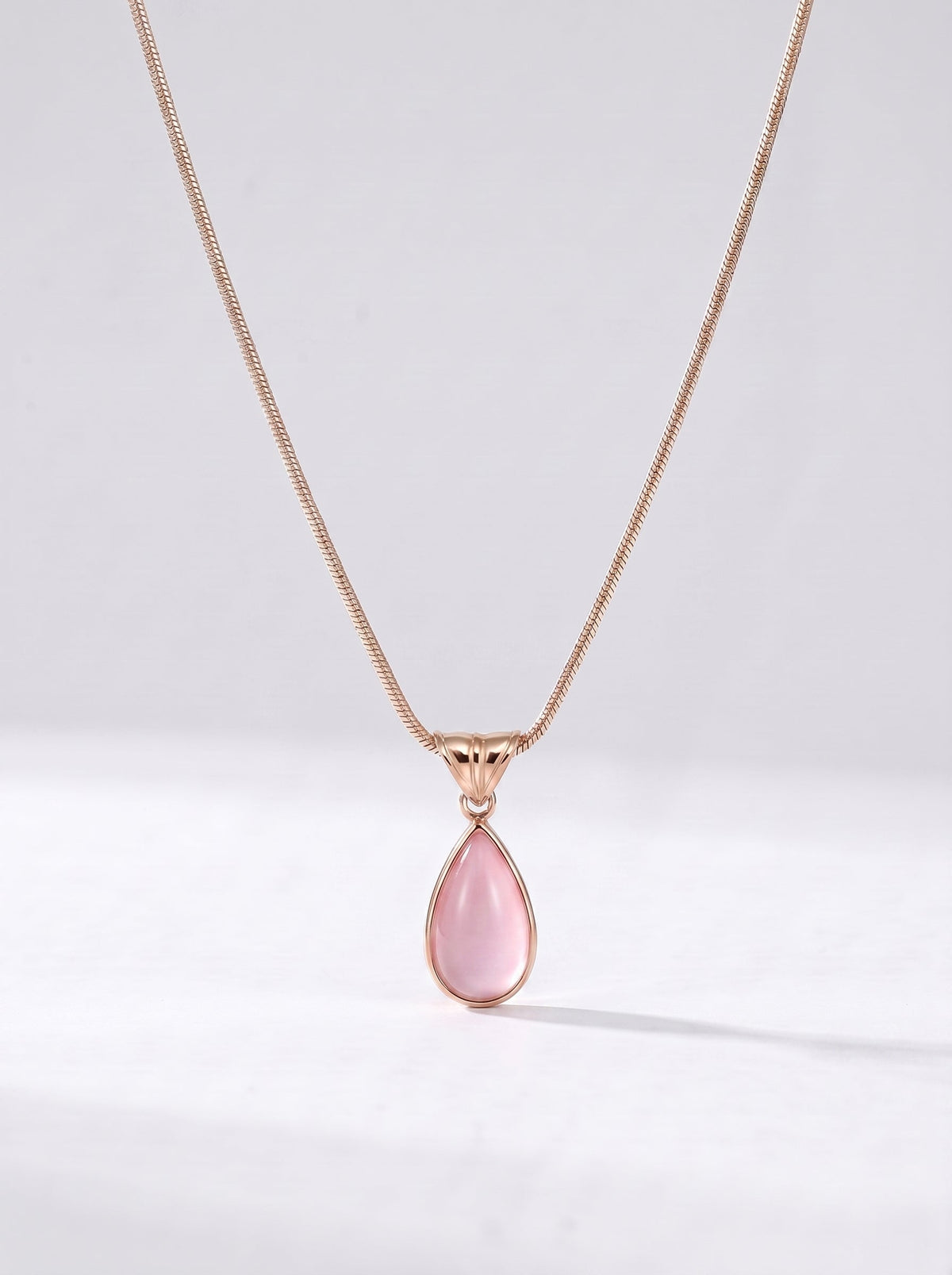 Collar dorado delicado con colgante rosa en forma de gota y acabado elegante, fotografiado sobre fondo claro para un look femenino, sofisticado y delicado.