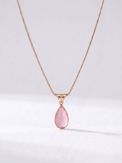 Collar dorado delicado con colgante rosa en forma de gota y acabado elegante, fotografiado sobre fondo claro para un look femenino, sofisticado y delicado.