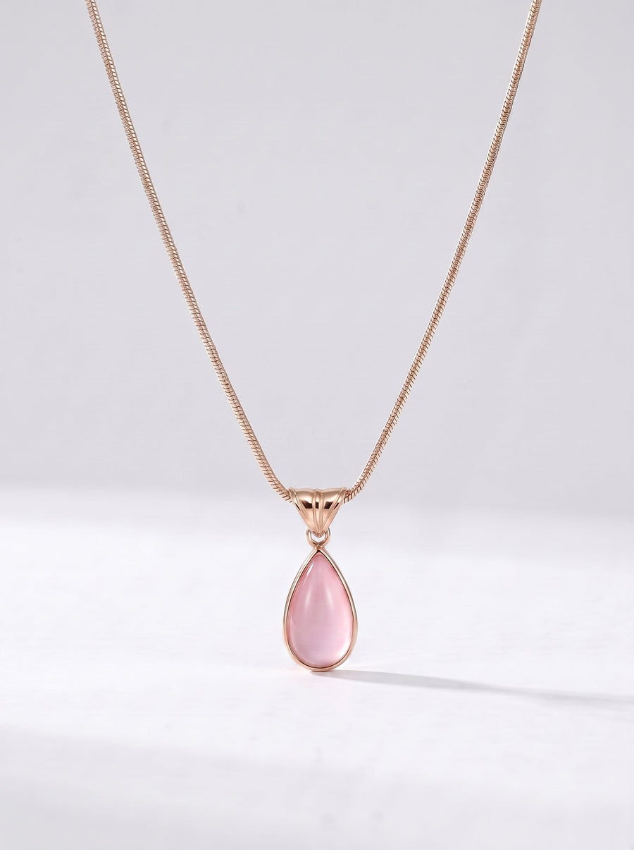 Collar dorado delicado con colgante rosa en forma de gota y acabado elegante, fotografiado sobre fondo claro para un look femenino, sofisticado y delicado.