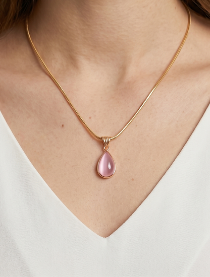 Collar dorado delicado con colgante rosa en forma de gota y acabado elegante, usado al cuello para un look femenino, sofisticado y delicado.
