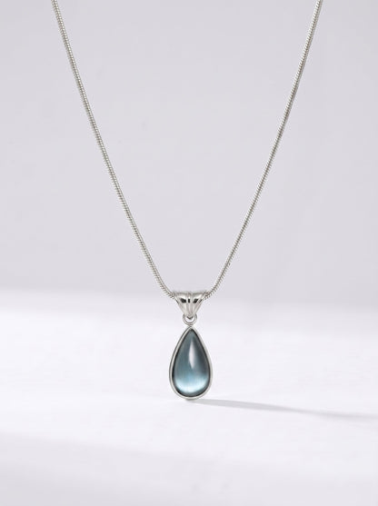 Collar plateado delicado con colgante azul en forma de gota y acabado elegante, fotografiado sobre fondo claro para un look sofisticado, moderno y delicado.