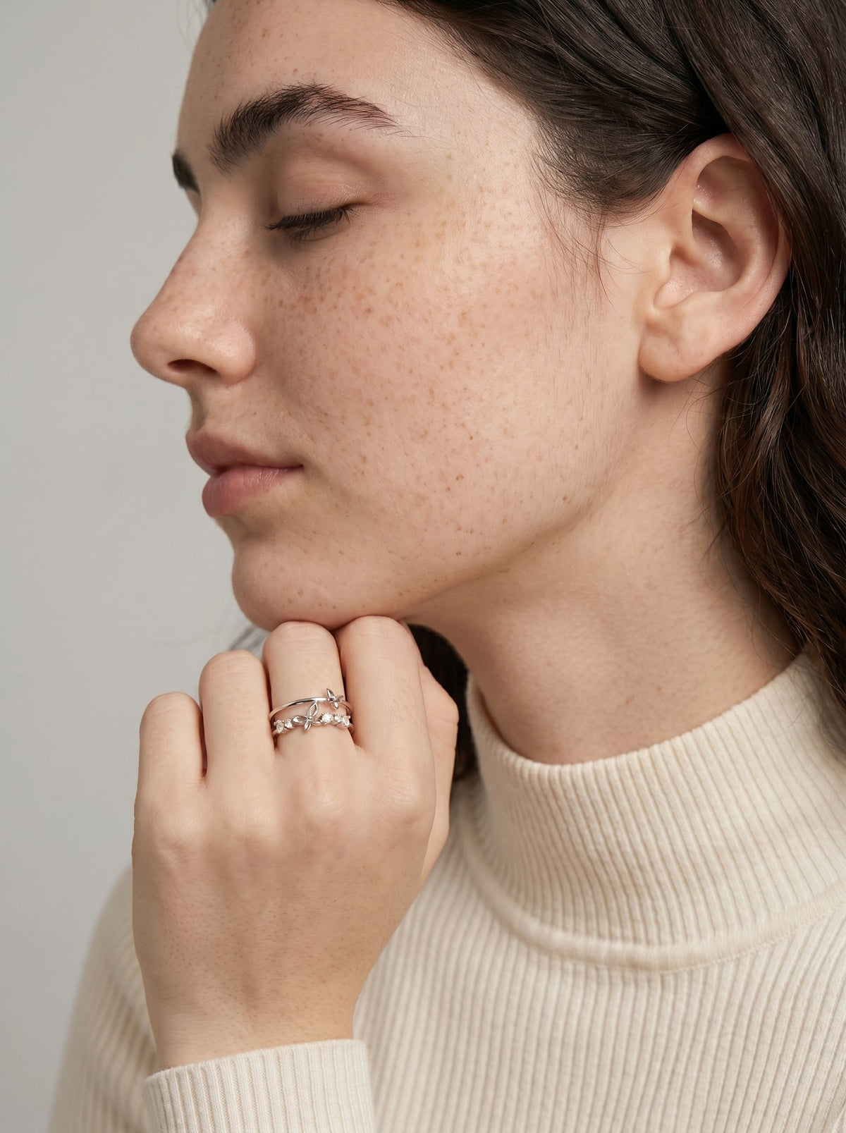 Primer plano de una persona con un anillo sobre un fondo neutro.

