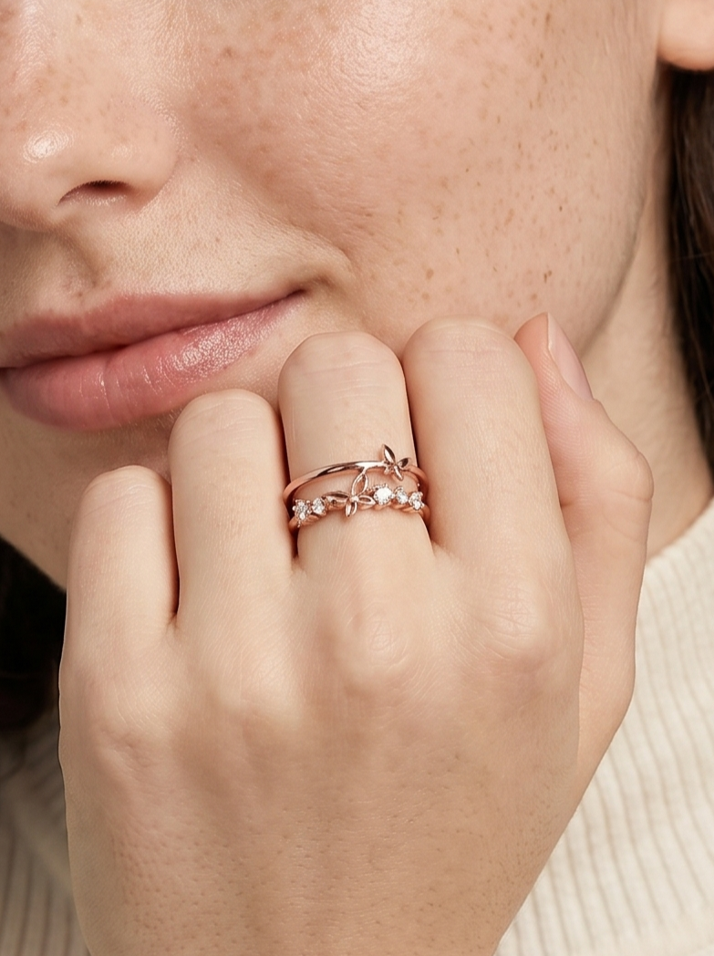 Primer plano de una mano con un anillo de oro rosa con un diamante, tocando el mentón.
