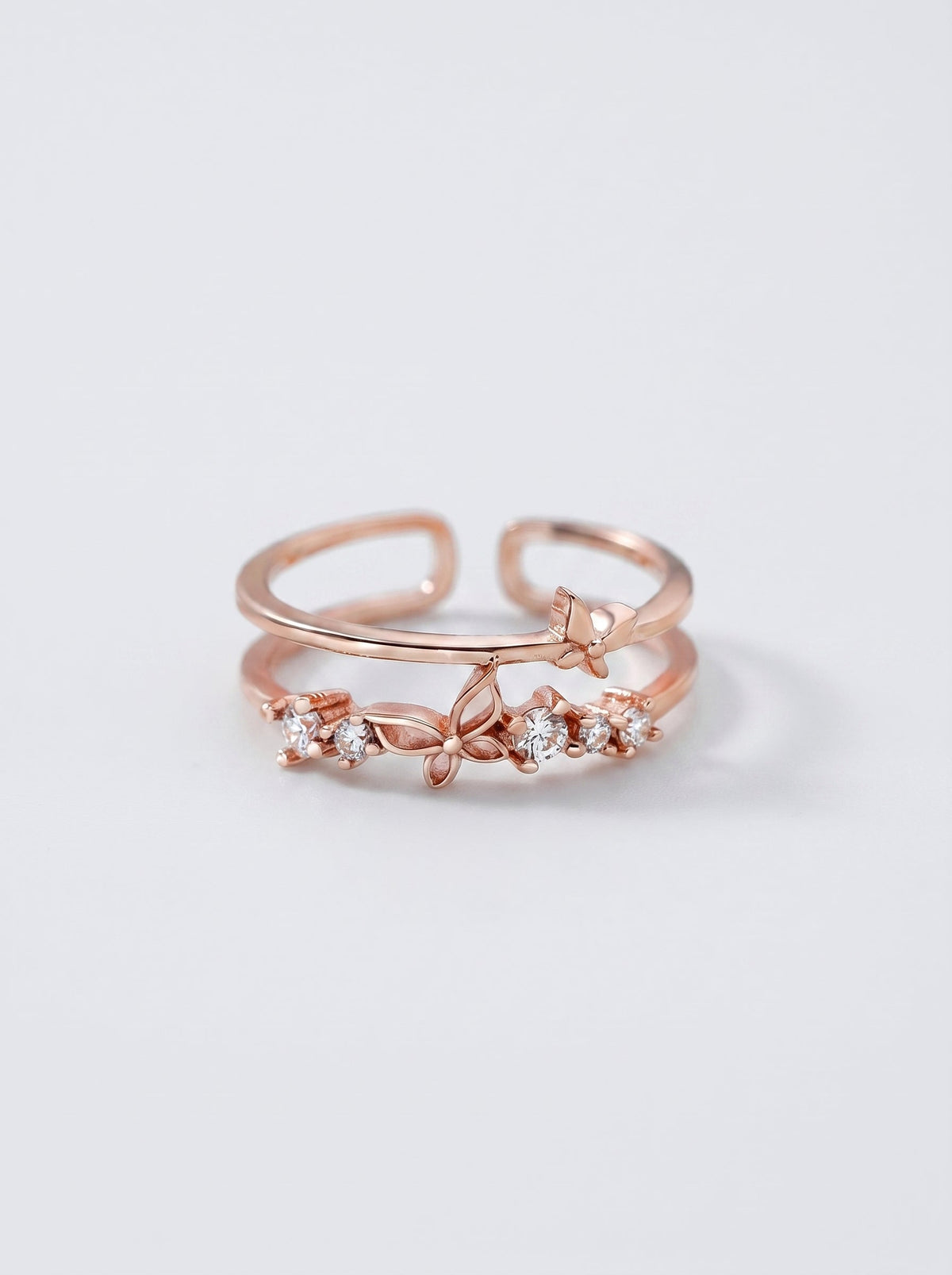 Anillo en oro rosa con detalles en diamante sobre fondo gris claro.
