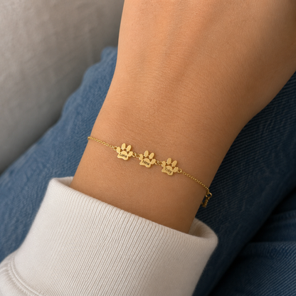 Pulsera con Huellas y nombres dorada — 3 Huellas con los nombres Luna, Nina y Toby en la muñeca — lifestyle realista