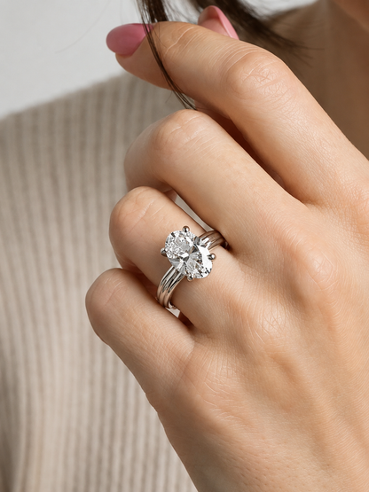 Primer plano de una mano con un anillo de diamantes sobre un fondo neutro.
