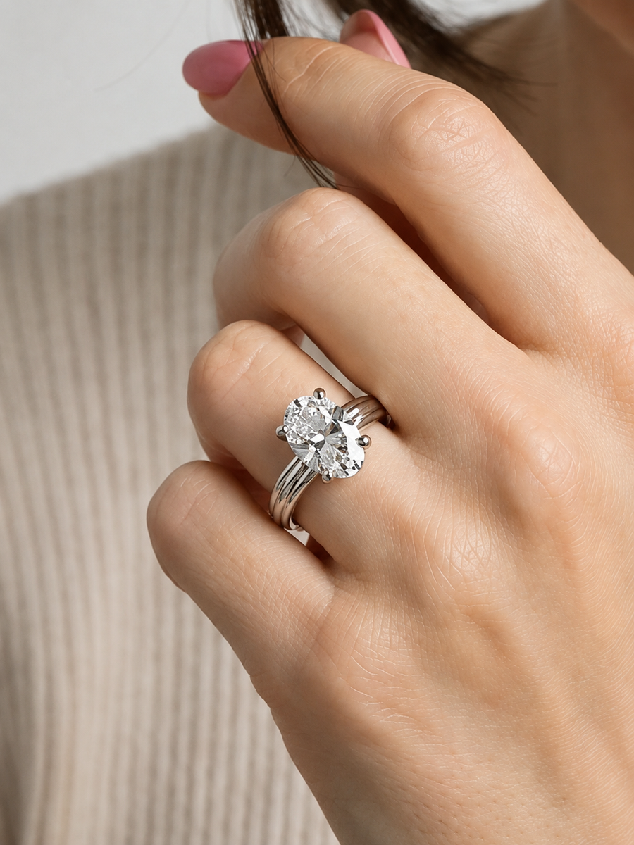 Primer plano de una mano con un anillo de diamantes sobre un fondo neutro.