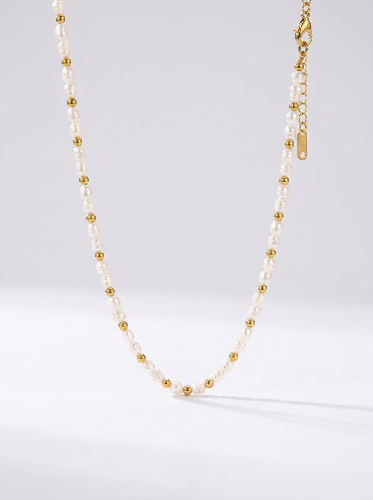 Collar delicado con perlas blancas naturales y detalles dorados, fotografiado sobre fondo claro para un look elegante, minimalista y sofisticado.