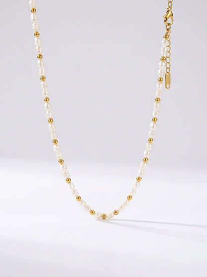Collar delicado con perlas blancas naturales y detalles dorados, fotografiado sobre fondo claro para un look elegante, minimalista y sofisticado.