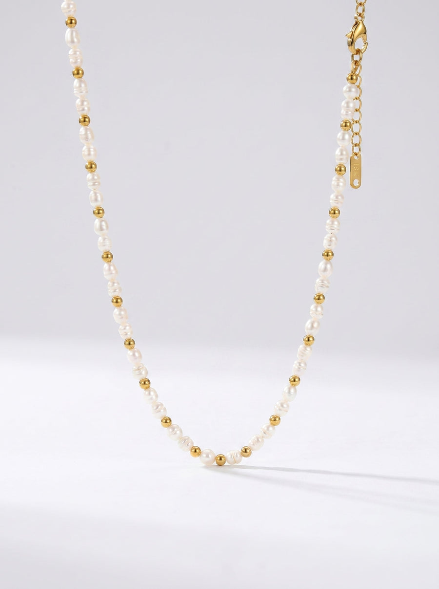Collar delicado con perlas blancas naturales y detalles dorados, fotografiado sobre fondo claro para un look elegante, minimalista y sofisticado.