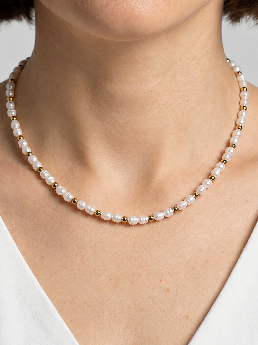 Collar delicado con perlas blancas naturales y detalles dorados, usado al cuello para un look elegante, minimalista y sofisticado.