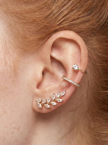 Detalle de una oreja con varios pendientes de diamantes sobre un fondo neutro.
