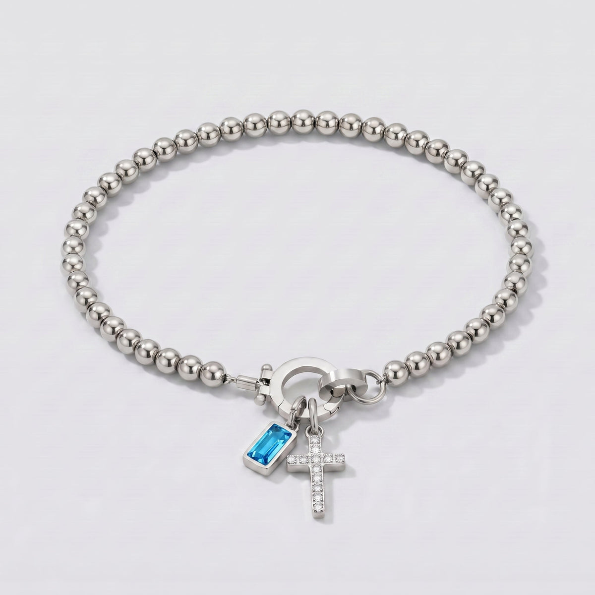 Pulsera plateada de cuentas con cruz y piedra de nacimiento topacio azul de diciembre.