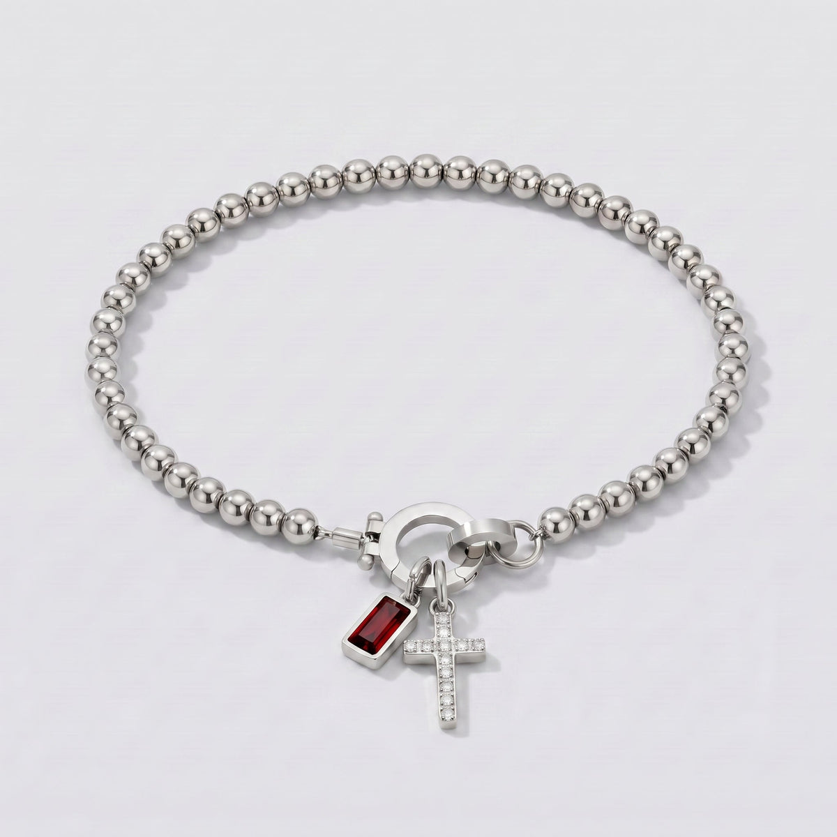 Pulsera plateada de cuentas con cruz y piedra de nacimiento granate rojo de enero.