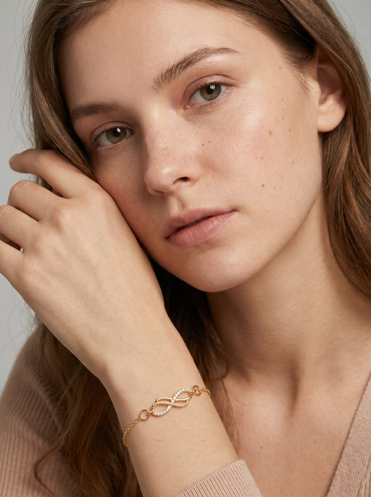 Pulsera dorada delicada con símbolo infinito, cadena fina y acabado brillante, usada por una modelo para un look elegante, femenino y minimalista.