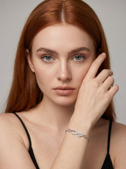 Pulsera plateada delicada con símbolo infinito, detalle en cristales y cadena fina, usada por una modelo para un look elegante, femenino y minimalista.