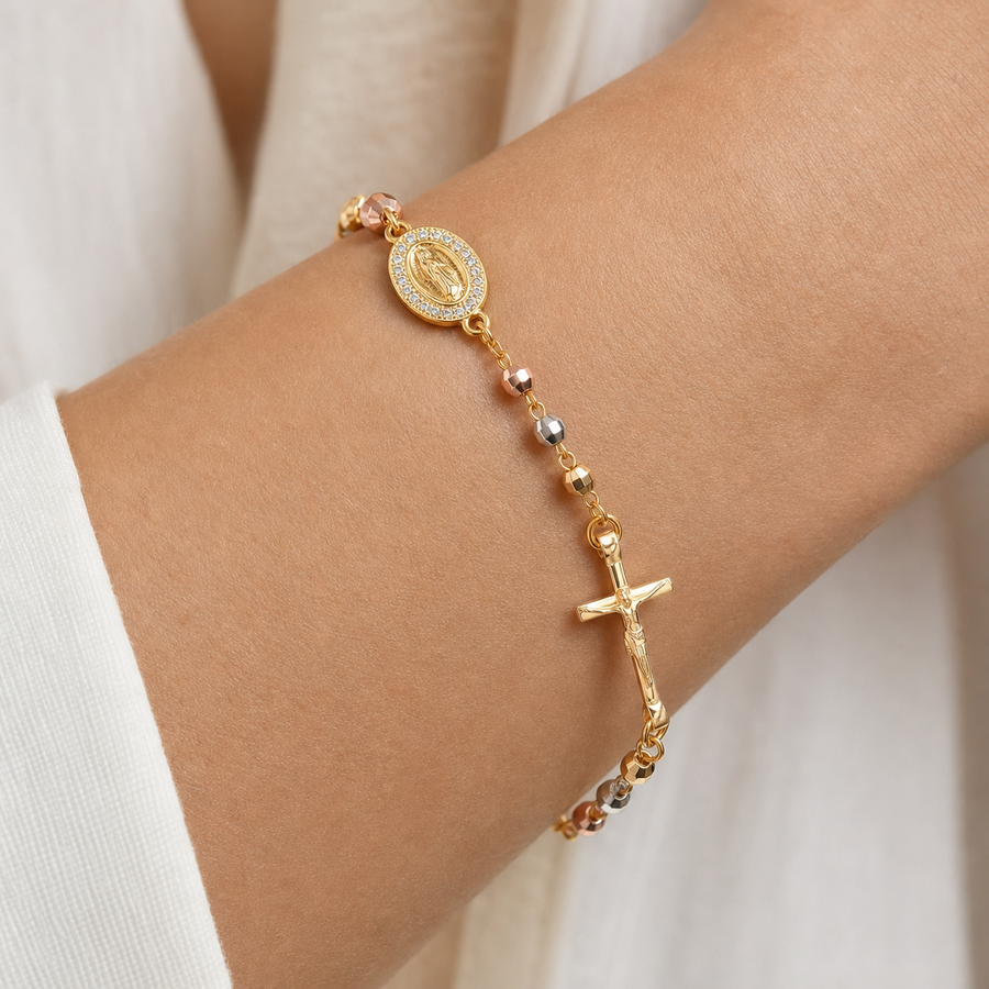 Mujer luciendo la Pulsera Ave María en la muñeca — medalla de la Virgen, crucifijo y cuentas tricolor.