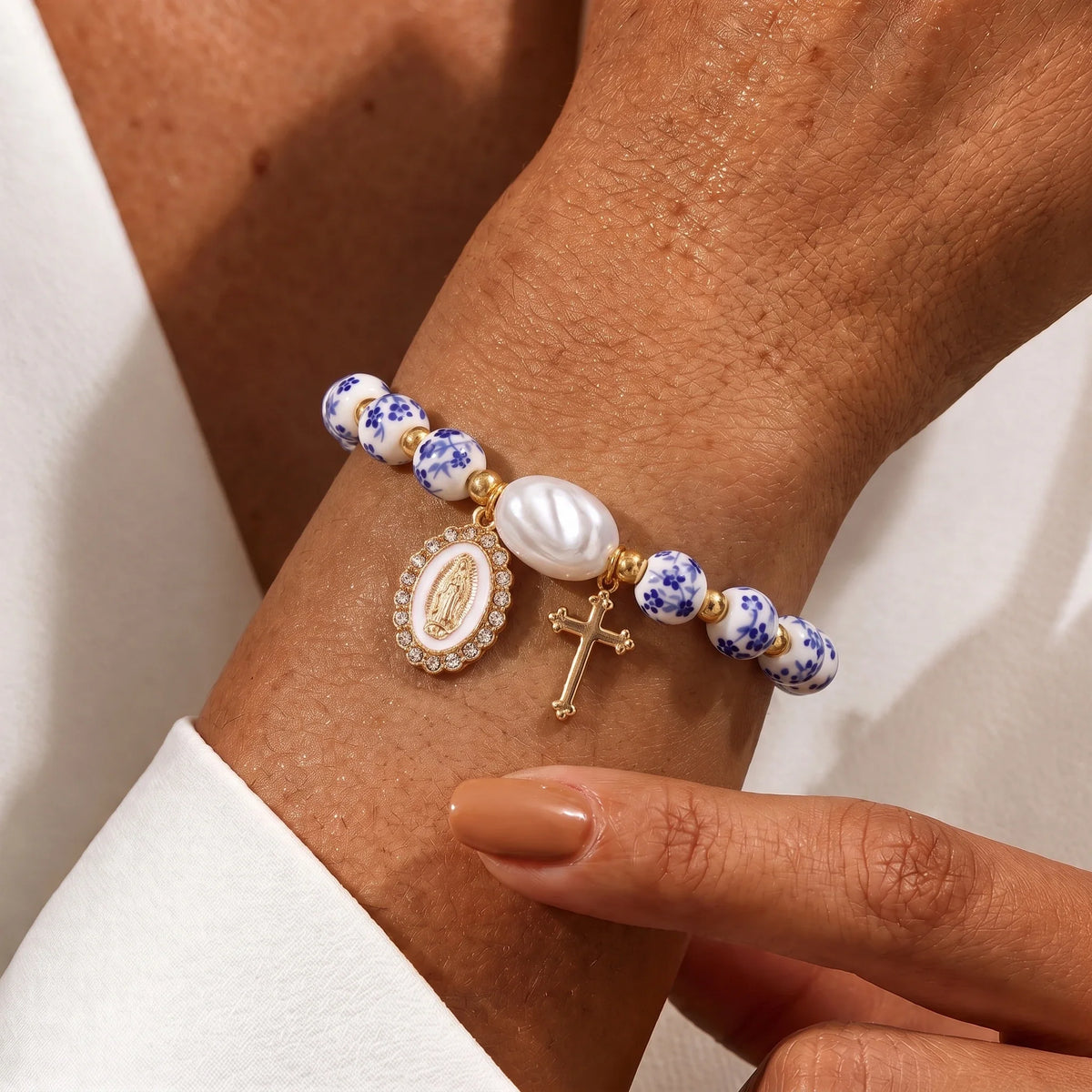Pulsera cerámica española con medalla de la Virgen María y cruz en uso en la muñeca