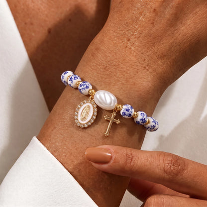 Pulsera cerámica española con medalla de la Virgen María y cruz en uso en la muñeca