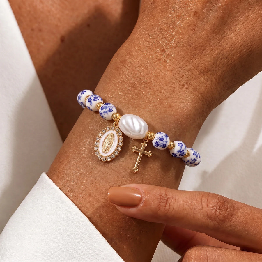 Pulsera cerámica española con medalla de la Virgen María y cruz en uso en la muñeca