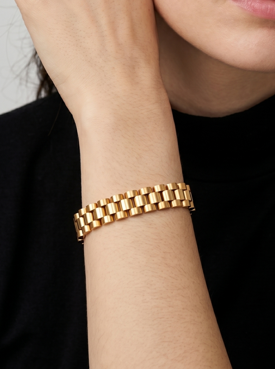 Pulsera dorada con diseño de eslabones anchos y acabado brillante, usada en la muñeca para un look elegante y sofisticado.