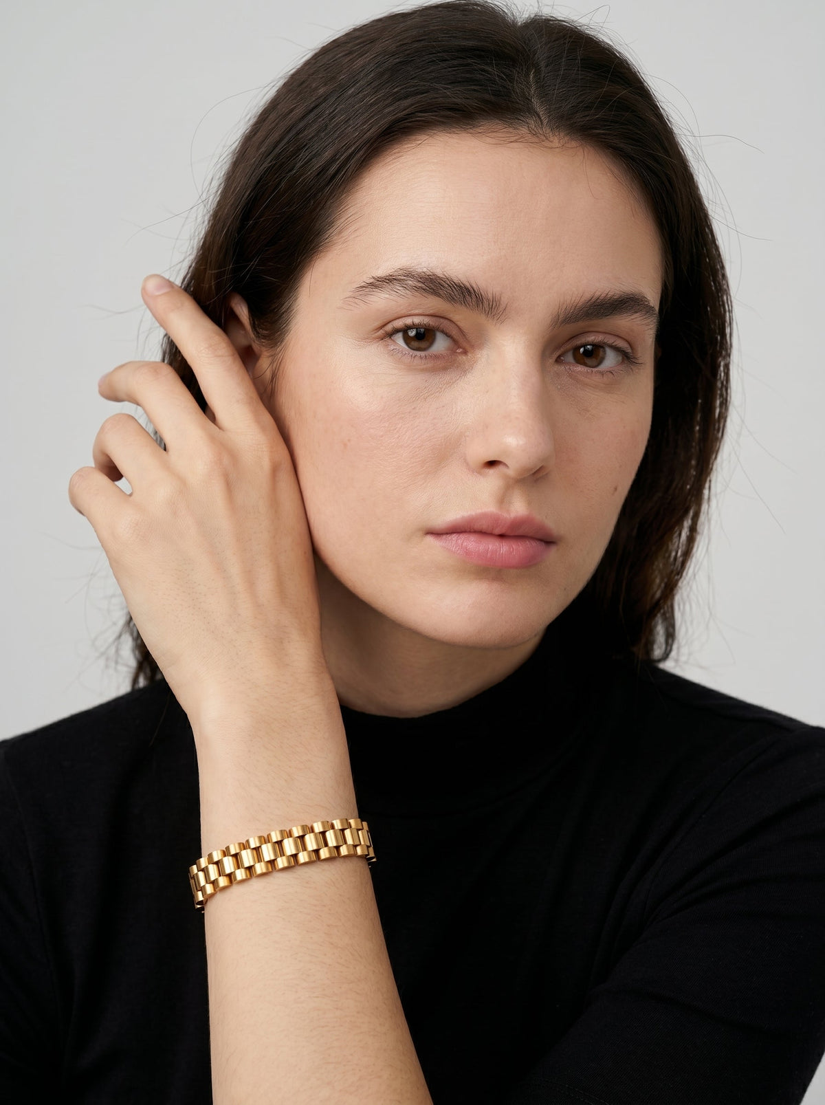 Pulsera dorada con diseño de eslabones anchos y acabado brillante, usada por una modelo para un look elegante y sofisticado.