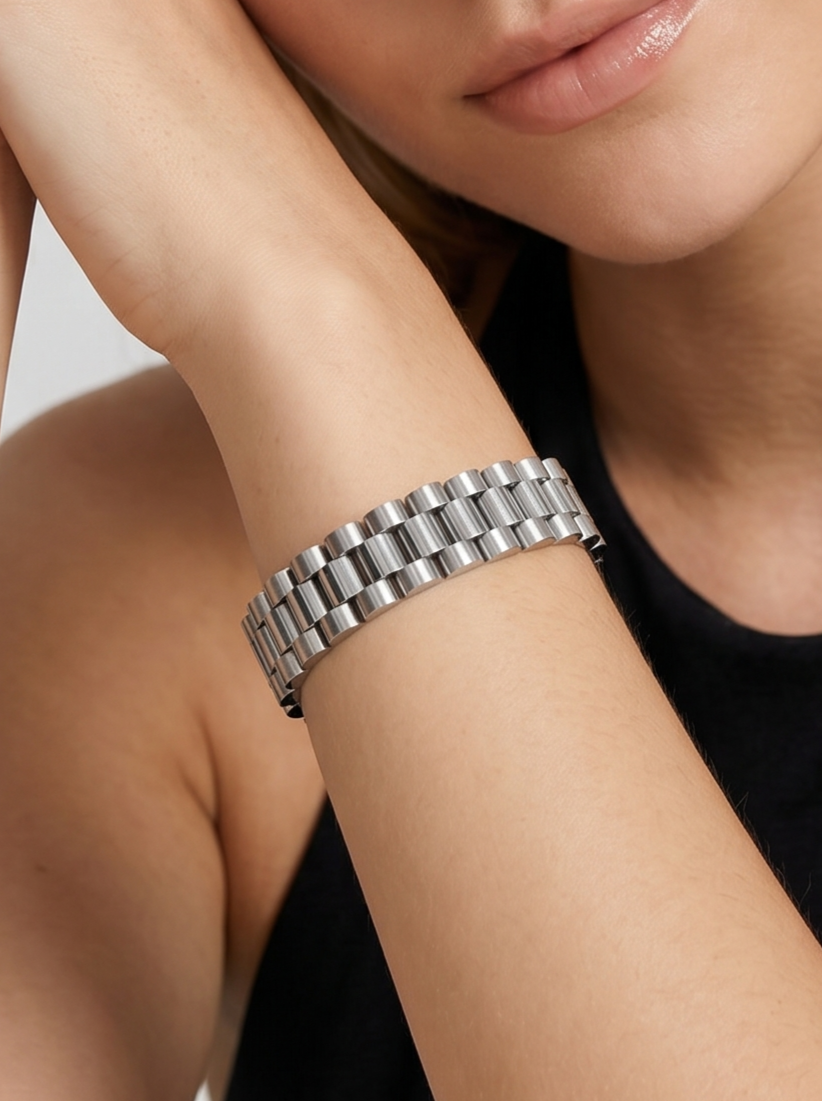 Pulsera plateada con diseño de eslabones anchos y acabado brillante, usada en la muñeca para un look elegante y sofisticado.