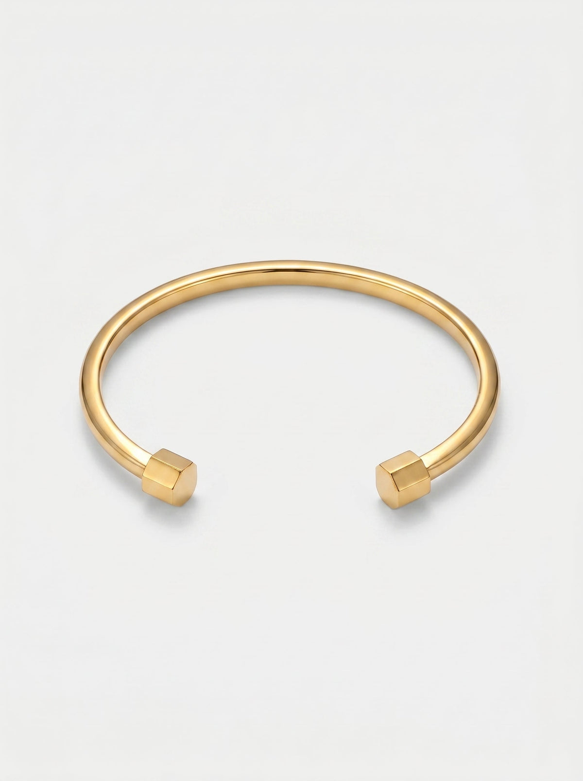 Pulsera dorada rígida con diseño abierto, acabado pulido y extremos hexagonales, fotografiada sobre fondo claro para un look minimalista y moderno.