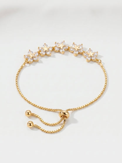 Pulsera dorada delicada con flores de cristales, cadena ajustable y acabado brillante, fotografiada sobre fondo claro para un look femenino, elegante y luminoso.